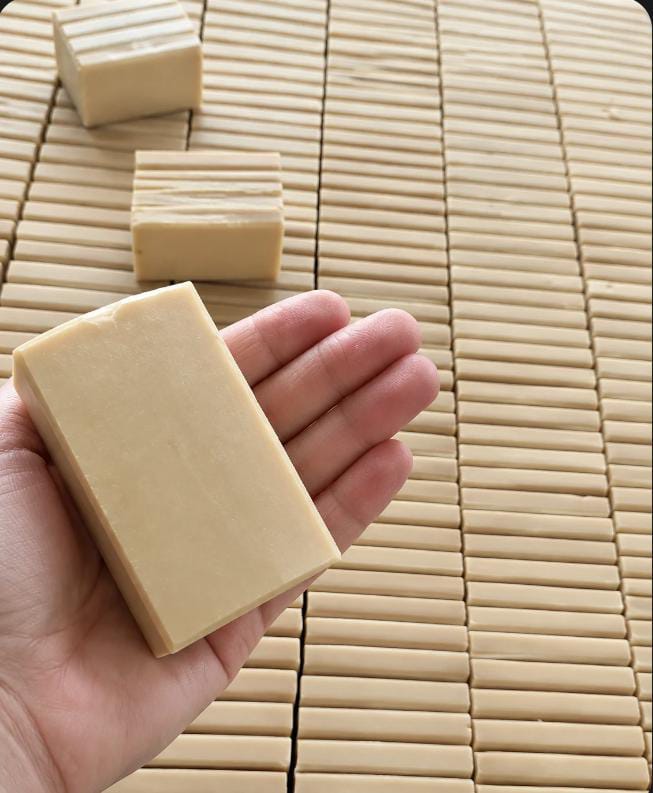 Bar soap held in hand above rows of soap